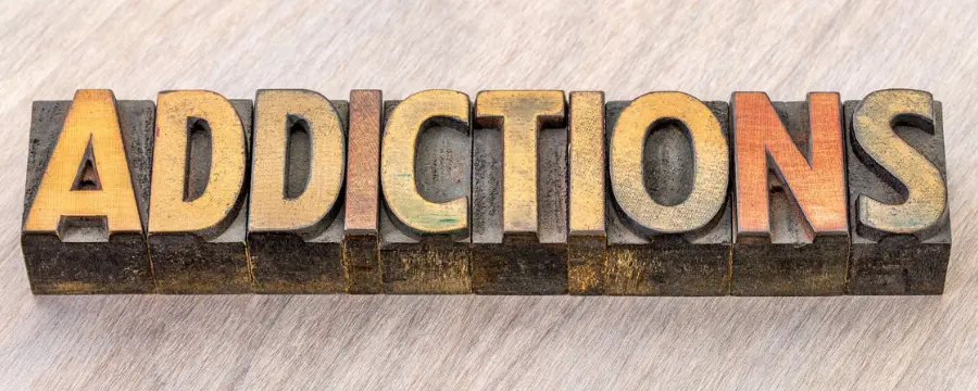 Addictions spelled out in wooden block letters in representation of different types of addictions.