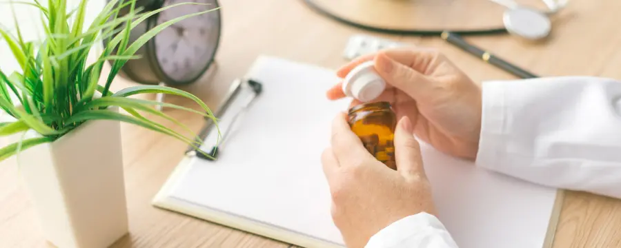 Doctor checking pill bottle while assessing benzo withdrawal symptoms of patient out of frame