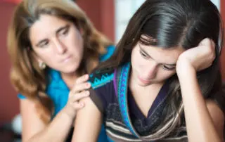 Lady comforting girl. Support your loved one's recovery by understanding common addiction relapse triggers.