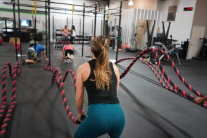Woman exercising with red and black ropes.