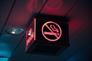 Four-sided No-Smoking sign lit up with red lettering on left side and No-Smoking symbol on the front, hanging from a ceiling.