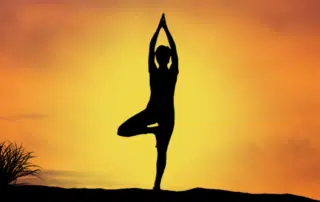 A woman standing on one leg with her arms raised above her doing a yoga pose.
